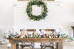 Bride and Groom Sweetheart Table with Wooden Farm Table with Mr. and Mrs. Sign and Table Garland | Greenery Plant Wedding Wreath Decor with Wedding Sign | Rustic, Country Wedding Inspiration | Tampa Bay Wedding Reception | Florist Cotton & Magnolia