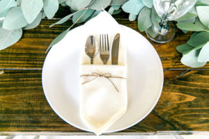 Place Setting with White Napkin in Twine Rope with Garland Greenery Centerpieces and Wooden Farm Tables | Rustic, Country Wedding Reception Decor Inspiration