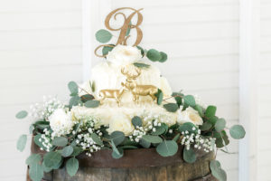 White Buttercream Wedding Cake with Wooden Initial Cake Topper and Hunting Deer on Oak Wooden Barrel | Rustic, Country Wedding Reception Decor Inspiration