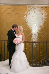 Bride and Groom Kiss Wedding Portrait by Modern White Chandelier with Pink Rose Bouquet | Elegant Downtown Tampa Wedding Venue The Tampa Club | Tampa Bay Wedding Photographer Carrie Wildes Photography | Wedding Florist Northside Florist