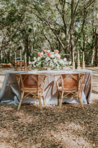Peach and Blush Pink Wedding Centerpieces with Greenery, Candles, Wicker Chairs and Shimmery Neutral Linens | Retro Vintage Boho Wedding Inspiration | Tampa Wedding Florist Northside Florist | Planner Glitz Events | Outdoor Venue Casa Lantana | Over the Top Linen Rentals