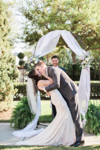 Bride and Groom First Kiss Wedding Ceremony Portrait Under Fabric Ceremony Arch