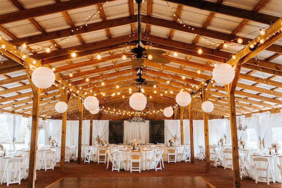 Outdoor, Florida Barn Wedding Reception Venue with Market Lighting and White Lanterns with White Folding Chairs | Rustic Florida Wedding Venue Cross Creek Ranch