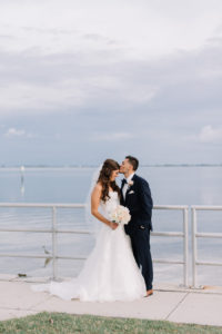 Outdoor Waterfront Wedding Couple Portrait with Watters Sweetheart Dress, Blush Rose Bouquet with Greenery, and Navy Suit at Tampa Bay Wedding Venue Safety Harbor Resort and Spa