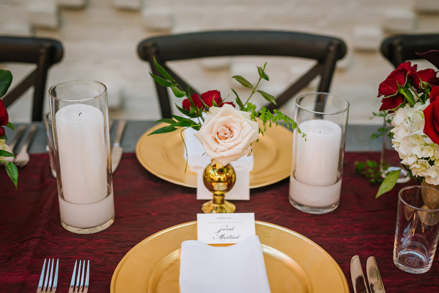 Elegant Rustic Great Gatsby Wedding Reception Table Decor with Gold Chargers, Pillar Candles in Glass Vases, and Small Blush, White Hydrangea and Red Rose Bouquet with Greenery in Short Gold Vase on Bordeaux Runner | Tampa Bay Wedding