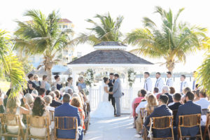 Outdoor Waterfront Gazebo Ceremony with Rustic Beach Wooden Folding Chairs and Gazebo, with Dramatic Mermaid Wedding Dress and Groomsmen with Blue Ties and Suspenders | Waterfront St Pete Wedding Venue Isla del Sol Yacht & Country Club