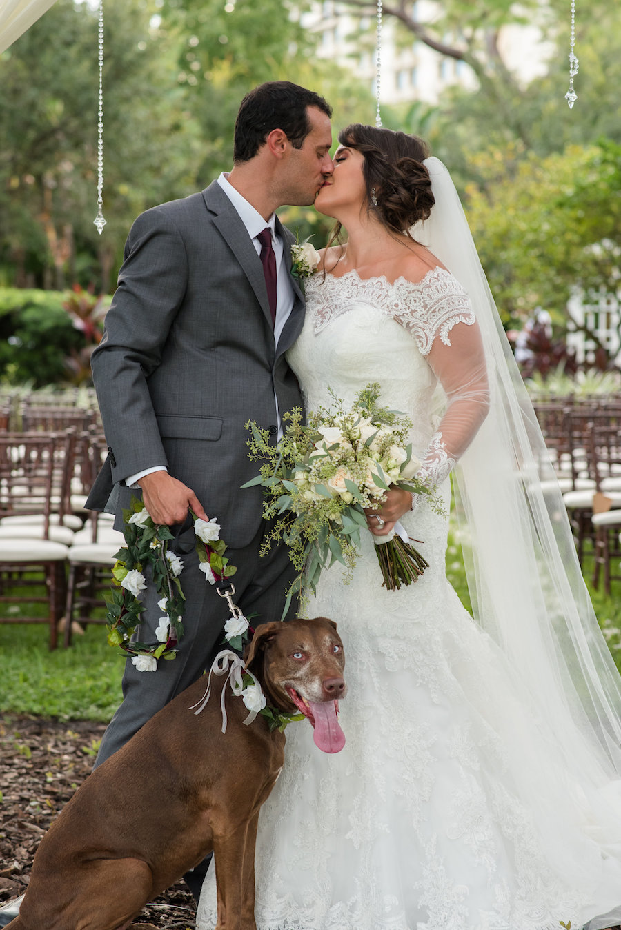Outdoor Garden Grey and Bordeaux Wedding Ceremony Portrait with Lace Sweetheart Allure Dress and White and Greenery Bouquet with Dog of Honor with Floral Garland Leash | Tampa Bay Florida Wedding Photographer Caroline & Evan Photography