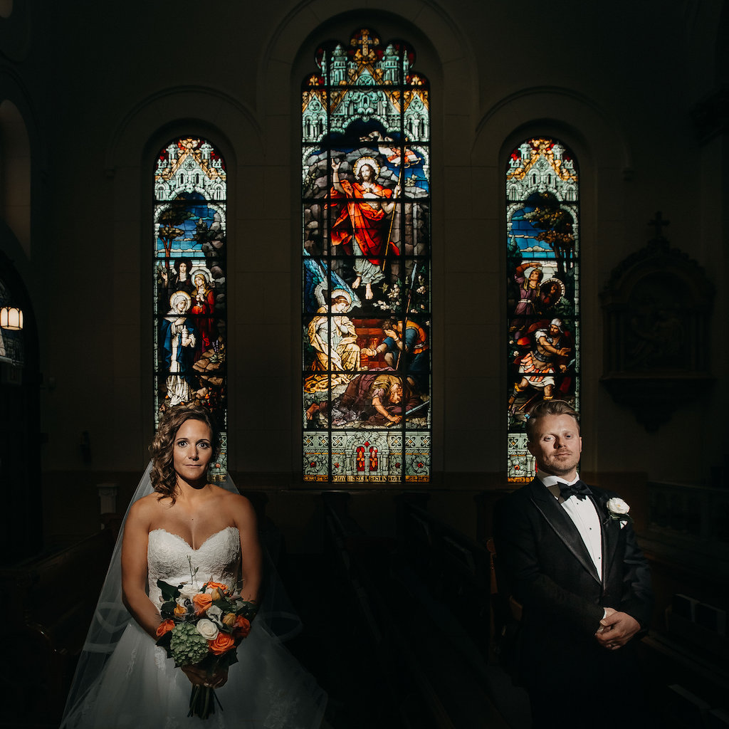 Wedding Ceremony Bride and Groom Portrait with Tropical Orange and Greenery BOuquet, White Boutonniere, Stained Glass Window | Tampa Bay Wedding Photography by Red Rad Creative