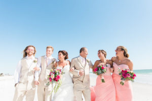 Siesta Key Beach Wedding Party Portrait with Blush Bridesmaids Dresses, Tan Linen Suits with Blush Ties and Peach Rose Boutonnière, and Tropical Fuchsia and Pink Rose Bouquets with Greenery | Sarasota Wedding Planner Parties A La Carte