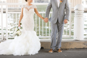 Outdoor Waterside Wedding Portrait with Beaded Mermaid Adrianna Papell Wedding Dress with Ivory Rose Bouquet with Succulents, Groom in Gray Suit with Brown Boat Shoes and Bird of Paradise Boutonnière