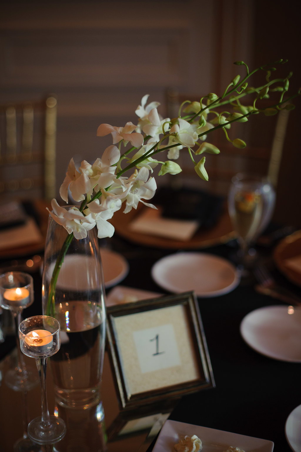 Elegant Black and White Wedding Reception Table Decor with Simple Vintage Wooden Frame Table Number, Simple Orchid Centerpiece in Tall Glass Vase, and Tall Glass Votive Candleholders | Tampa Bay Wedding