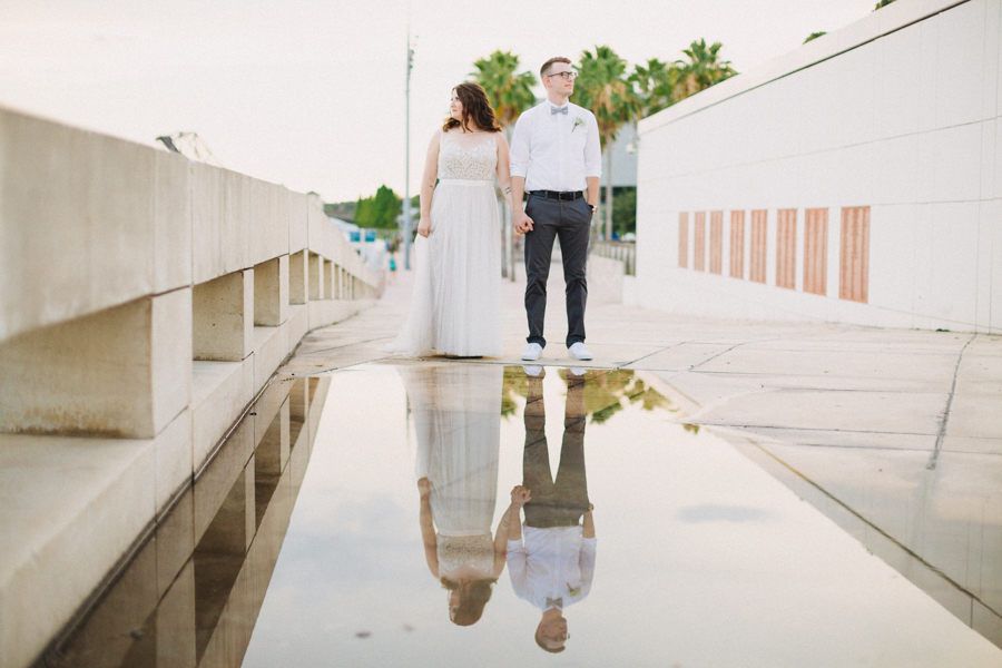 Downtown Tampa Outdoor Industrial Wedding Portrait with Groom in White Shirt with Gray Bowtie and Sneakers, Bride in Belted A Line Watters Wedding Dress