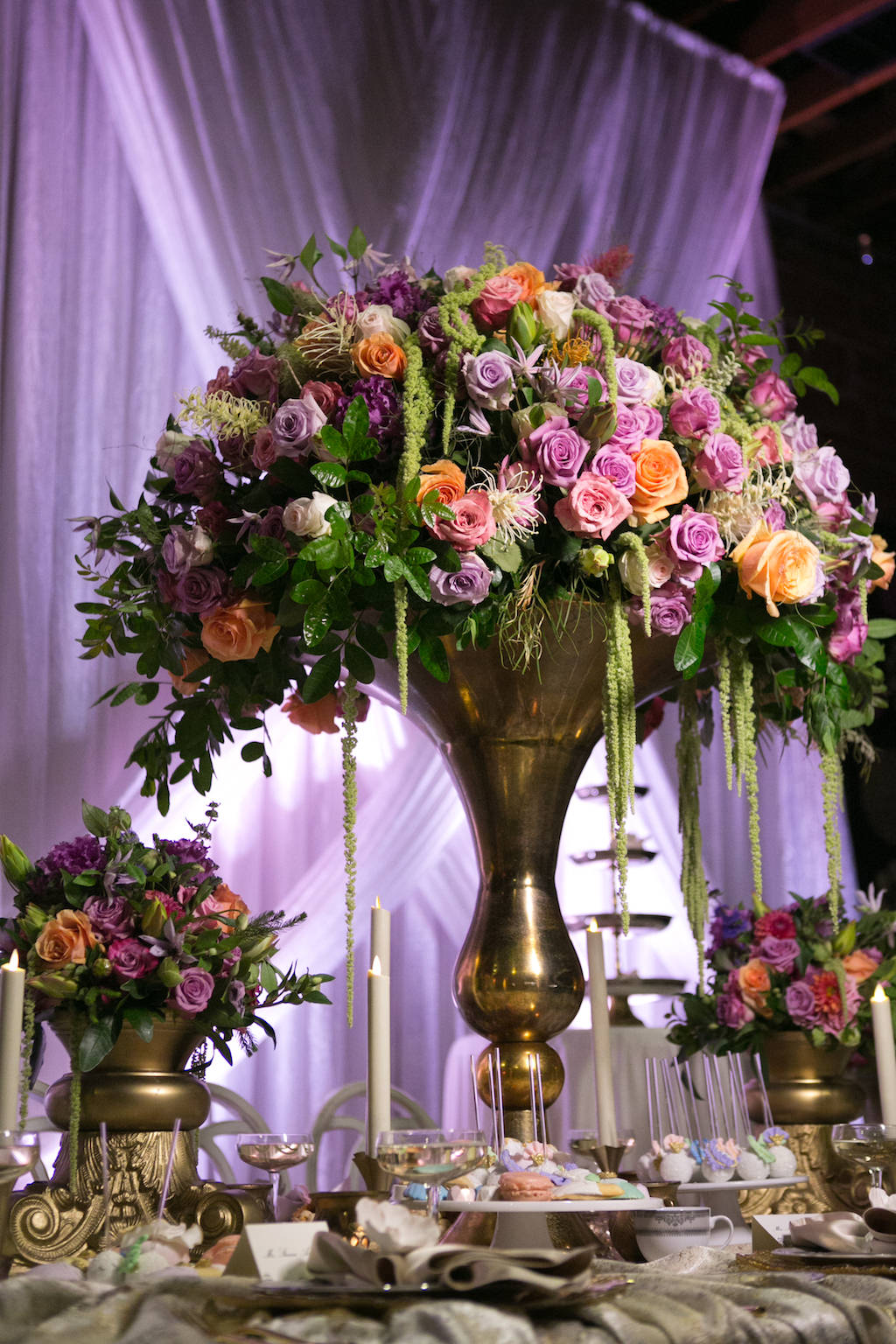 Tall Wedding Reception Centerpiece with Pink, Orange, and Purple Roses with Tropical Greenery