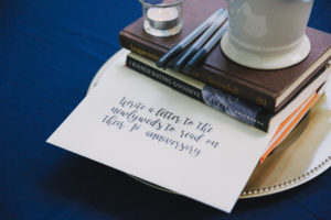 Modern Blue Wedding Reception Creative Table Marker Centerpiece with Books, Guestbook and Pens, and Handwritten Note