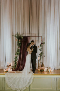 Deep Red Burgundy Wedding Ceremony Decor with Candles and Hanging Floral Rose Draped Altar Backdrop | Romantic Vintage Glam Wedding | Tampa Bay Wedding Planner Southern Glam Weddings & Events | Unique Tampa Bay Wedding Venue Safety Harbor Resort and Spa Theatre | Photographer Brandi Image Photography