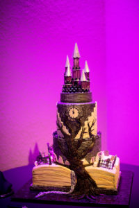 Halloween Themed Four Tiered Black and White Wedding Cake with Castle Cake Topper, Antique Clock and Tree decor, rising out of Old Book