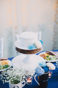 Bride and Groom Wedding Reception Blue and White Table Decor with Baby's Breath, Small Blue and White Flower Centerpiece, and Small Round White Wedding Cake on White Cake Stand