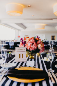 Black, White, and Gold Wedding Reception Table Decor with Elegant Printed Table Number Card, Low Tropical Floral Centerpiece in Round Gold Vase, and Striped Table Runner | Private Tampa Bay Wedding Venue The Centre Club