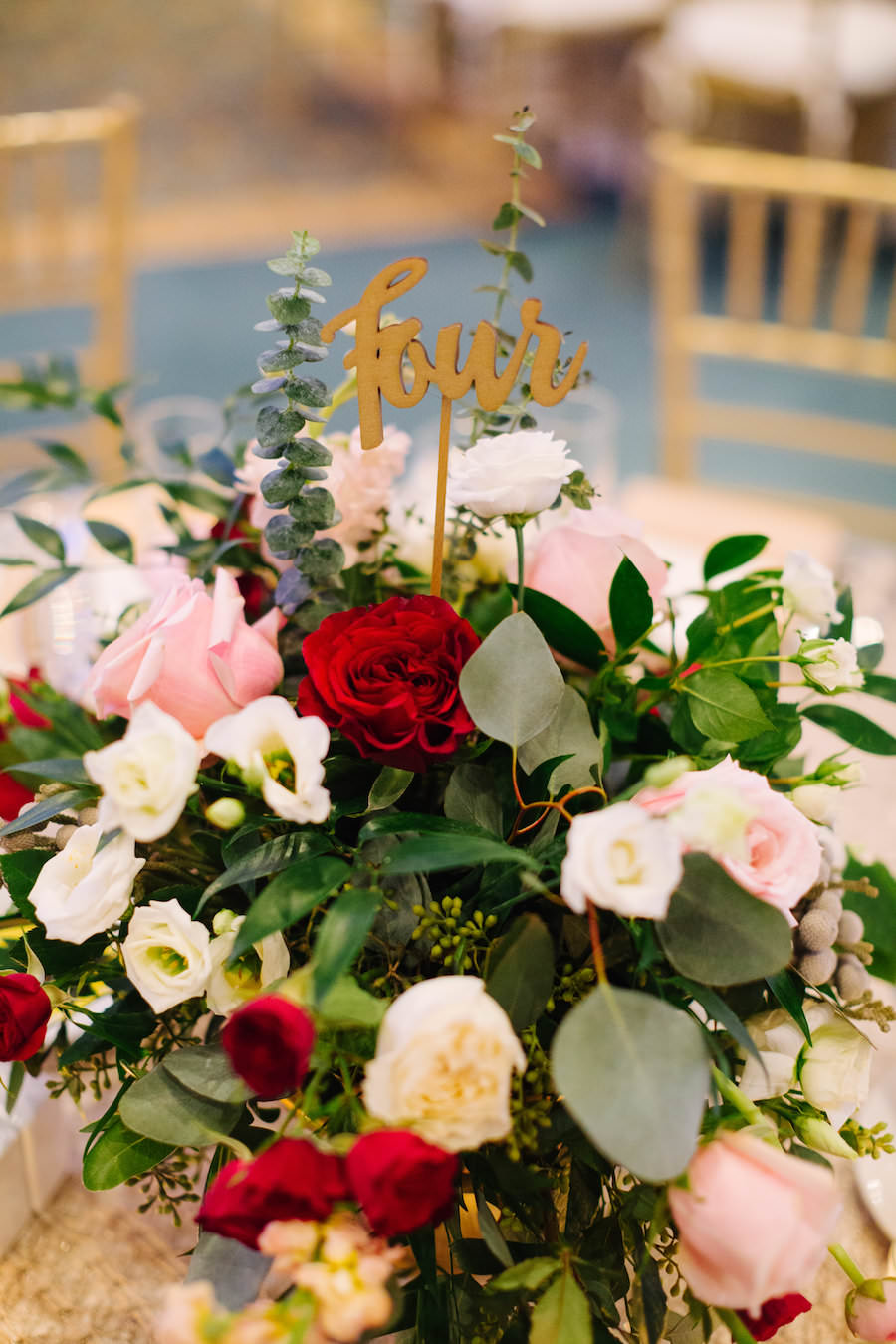 Wedding Reception Centerpiece Bouquet with Blush Pink, Red, and White Roses with Greenery and Stylish Gold Table Number