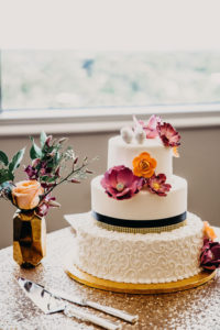 Three Tiered Round White Wedding Cake with Curly Cue Frosting and Black and Gold Stripe with Tropical Fuchsia and Orange Flowers on Gold Cake Stand | Tampa Bay Wedding