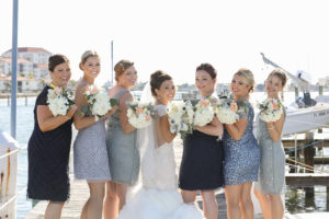 Outdoor Waterside Bridal Party Portrait with Mismatched Grey Toned Sequined Bridesmaids Dresses and Ivory Peach and Greenery Bouquets | Waterfront St. Pete Wedding Venue Isla Del Sol Yacht & Country Club
