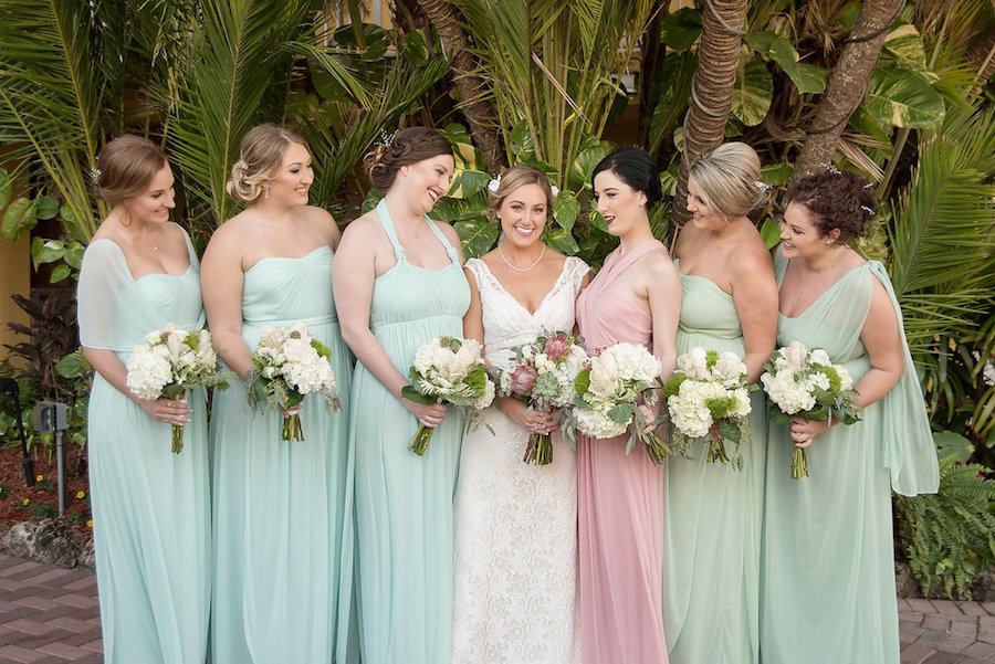 Bridal Party Portrait wearing Davids Bridal Lace V Neck Wedding Gown and Mismatched Davids Bridal Bridesmaids Dresses in Meadow Green, Mint, and Blush with White Rose and Succulent Bouquets | Romantic Pastel Beach Inspired Wedding | St Pete Wedding Photographer Kristen Marie Photography