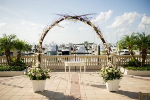 Waterfront Wedding Ceremony Decor with Natural Branch Arch and White and Pink Floral Decor | Historic Tampa Bay Wedding Venue Westshore Yacht Club