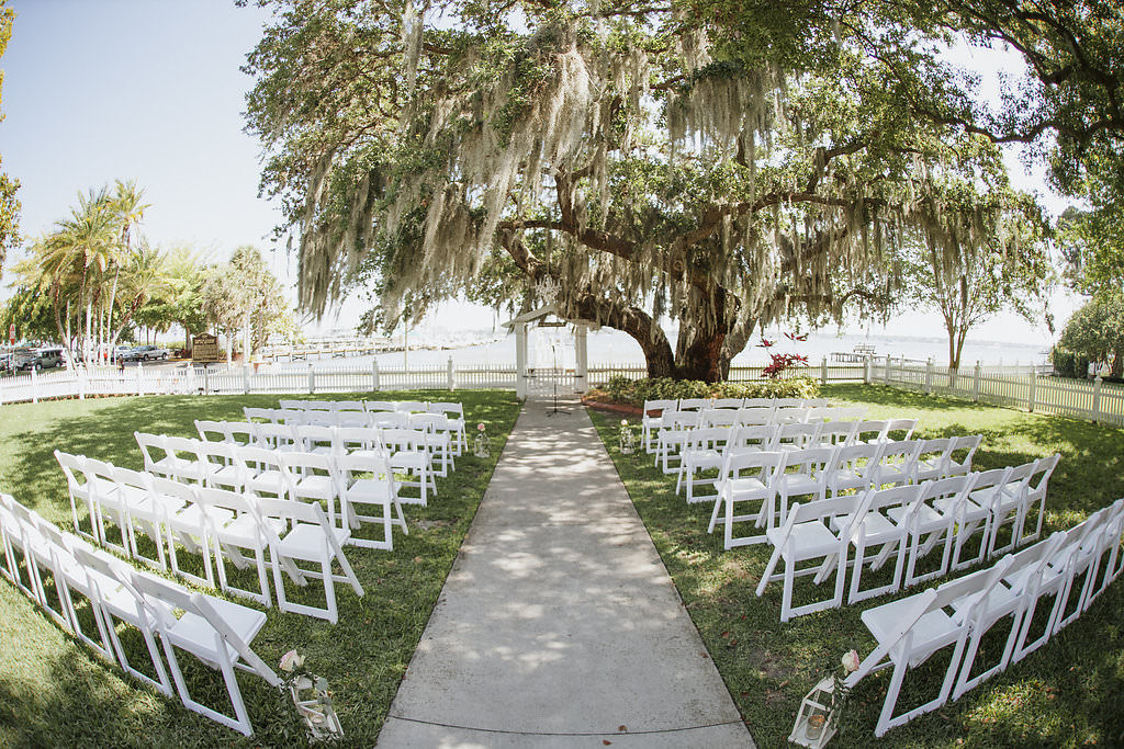 Outdoor Garden Waterfront Wedding Ceremony with Folding White Chairs and Storm Lanterns | Florida Venue Palmetto Riverside Bed and Breakfast | Tampa Bay Wedding Coordinator and Rentals Reserve Vintage Rentals