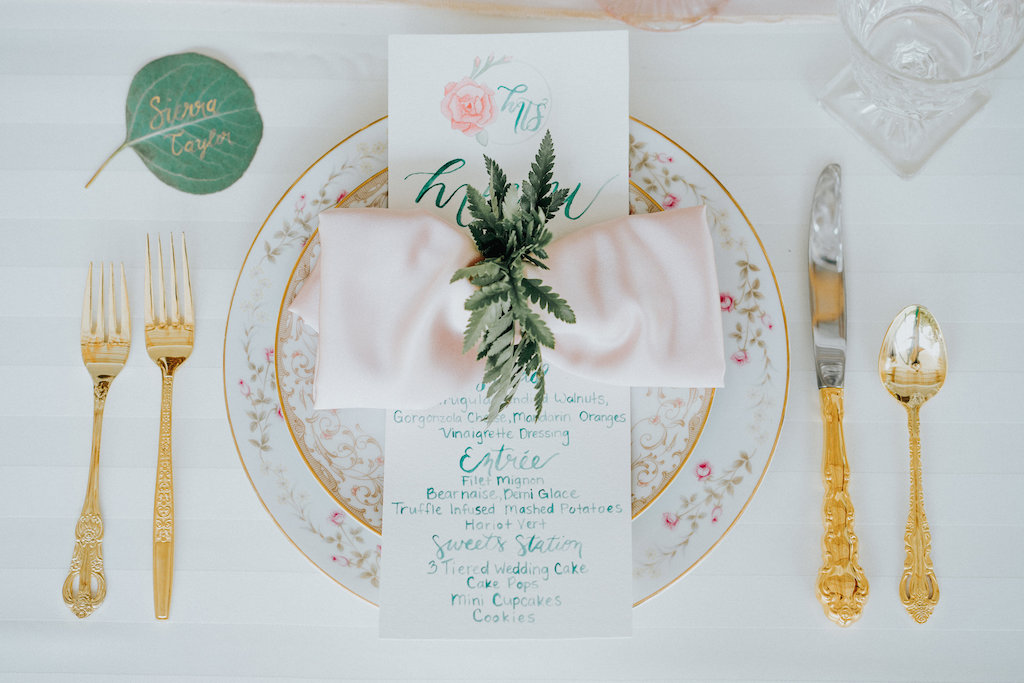 Elegant Rustic Wedding Reception Table Setting with Antique Gold Silverware and Painted Floral Plates, Hand-painted Leaf Place Card and Blue and Pink Menu, Blush Pink Napkin with Fern Napkin Ring | Sarasota Wedding Rentals Ever After Vintage Weddings