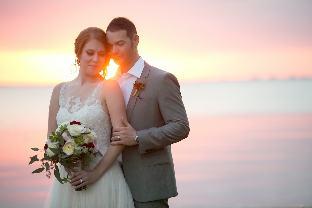 Waterfront Sunset Wedding Portrait with White, Pink, and Red Rose Bridal Bouquet with Greenery and Red Rose Boutonniere | Tampa Bay Florida Wedding Photographer Andi Diamond Photography | Hair and Makeup Michele Renee The Studio