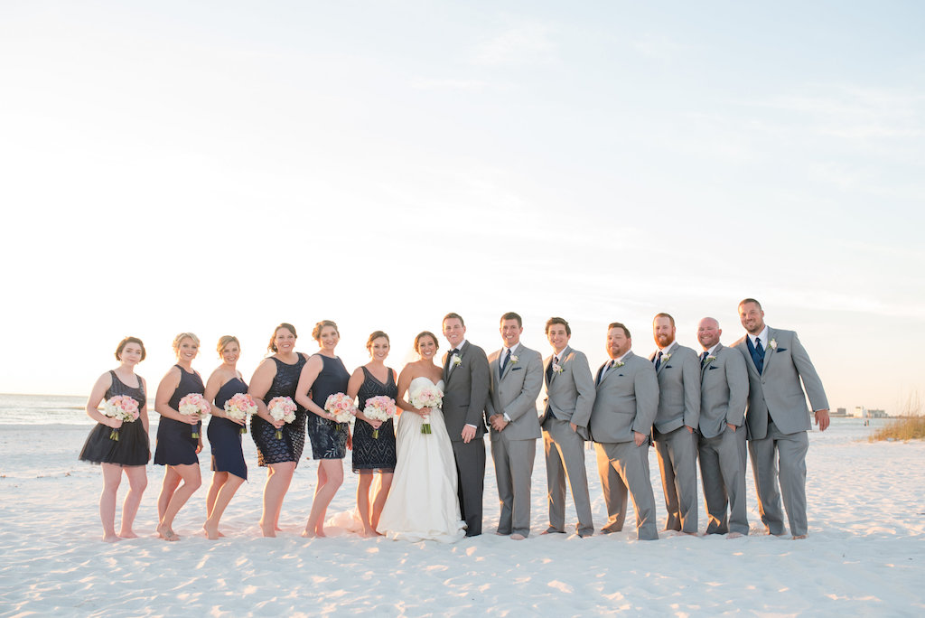 Wedding Party Outdoor Beach Portrait with Groomsmen in Gray Suits with Blue TIes, Bridesmaids in Short Mismatched Navy Blue Bridesmaids Dresses with Pink and White Rose Bouquet | Tampa Bay Wedding Photographer Caroline and Evan Photography