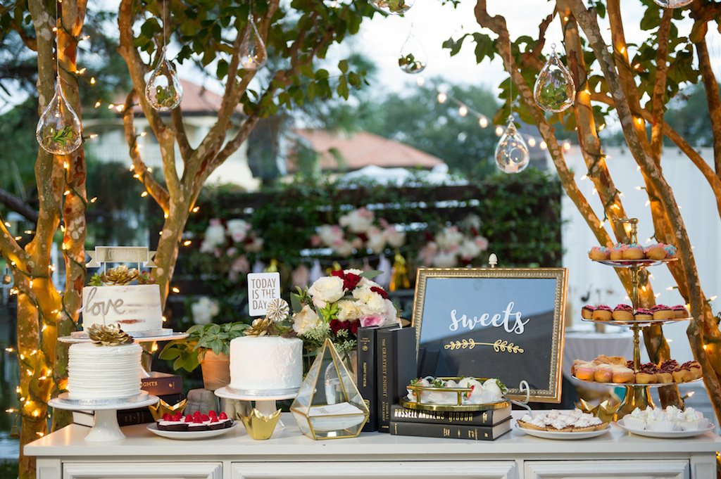 Outdoor Backyard Garden Wedding Reception Dessert Table with Cupcakes, Small Round White Cakes, Old books, Succulents, Hanging Glass Terrariums, and String Lights