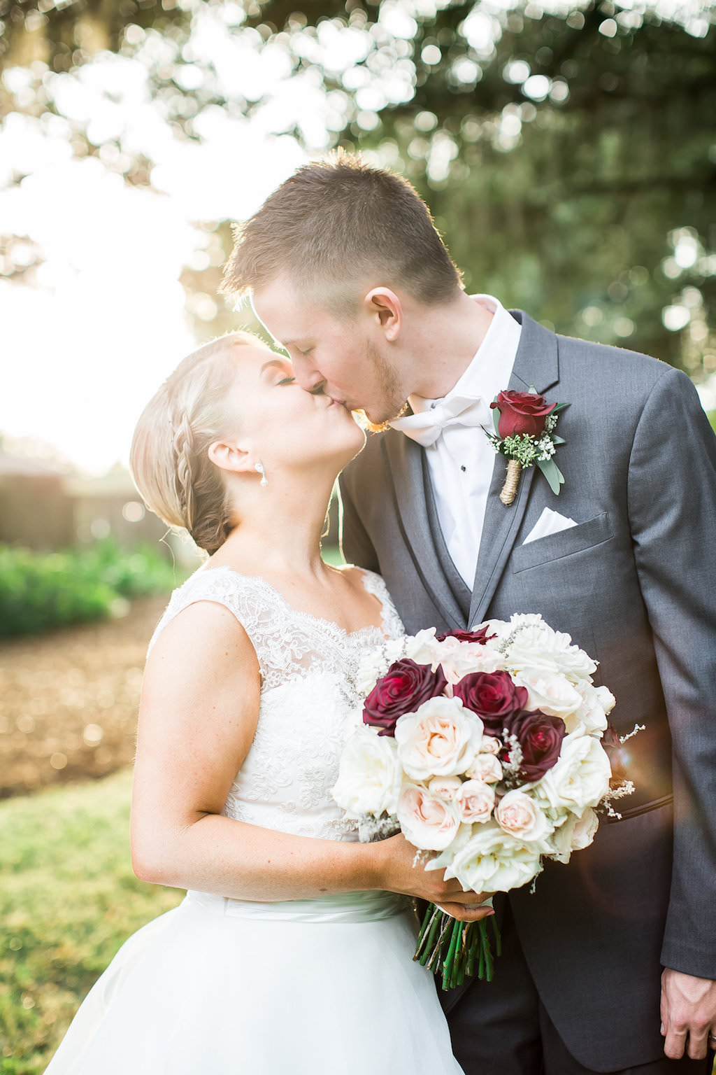 Bride and Groom Outdoor Garden Portrait with Groom in Gray Suit with White Bowtie and Red Rose Boutonniere, with Blush, Cream, and Burgundy Rose Bouquet | Tampa Bay Wedding Photographer Rad Red Creative