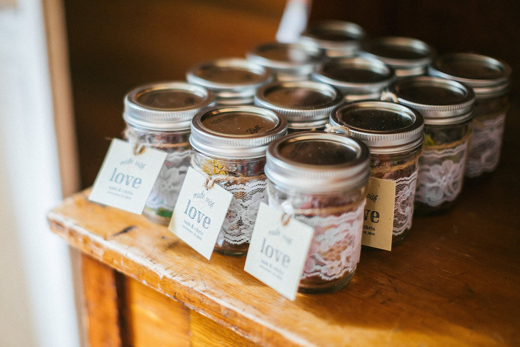 Rustic Farm Wedding Favor Table with Mason Jars Wrapped in Lace with Brown Paper Tags on Dresser