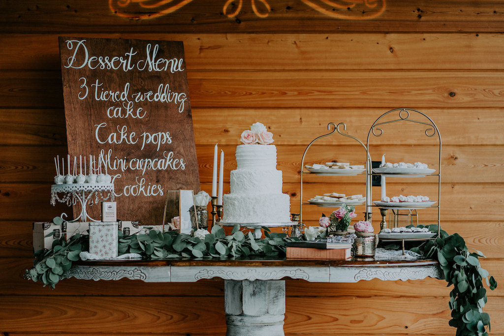 Elegant Rustic Barn Wedding Dessert Table Decor with Hand-painted Wooden Sign, Three Tier Round White Wedding Cake, Decorative Dessert Trays with Cake Pops, Mercury Votives and Leafy Garland
