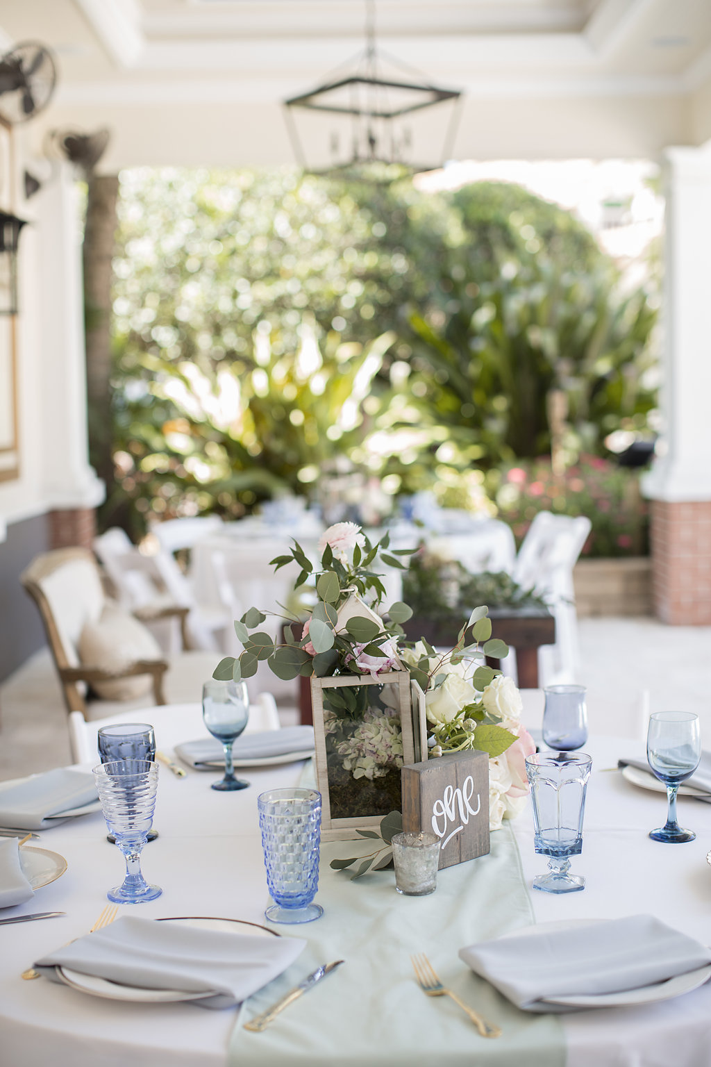 Romantic Vintage Outdoor Wedding Reception Decor | Mismatched Glassware and Wood Block Table Numbers and Greenery Centerpieces | Sarasota Reserve Vintage Rentals
