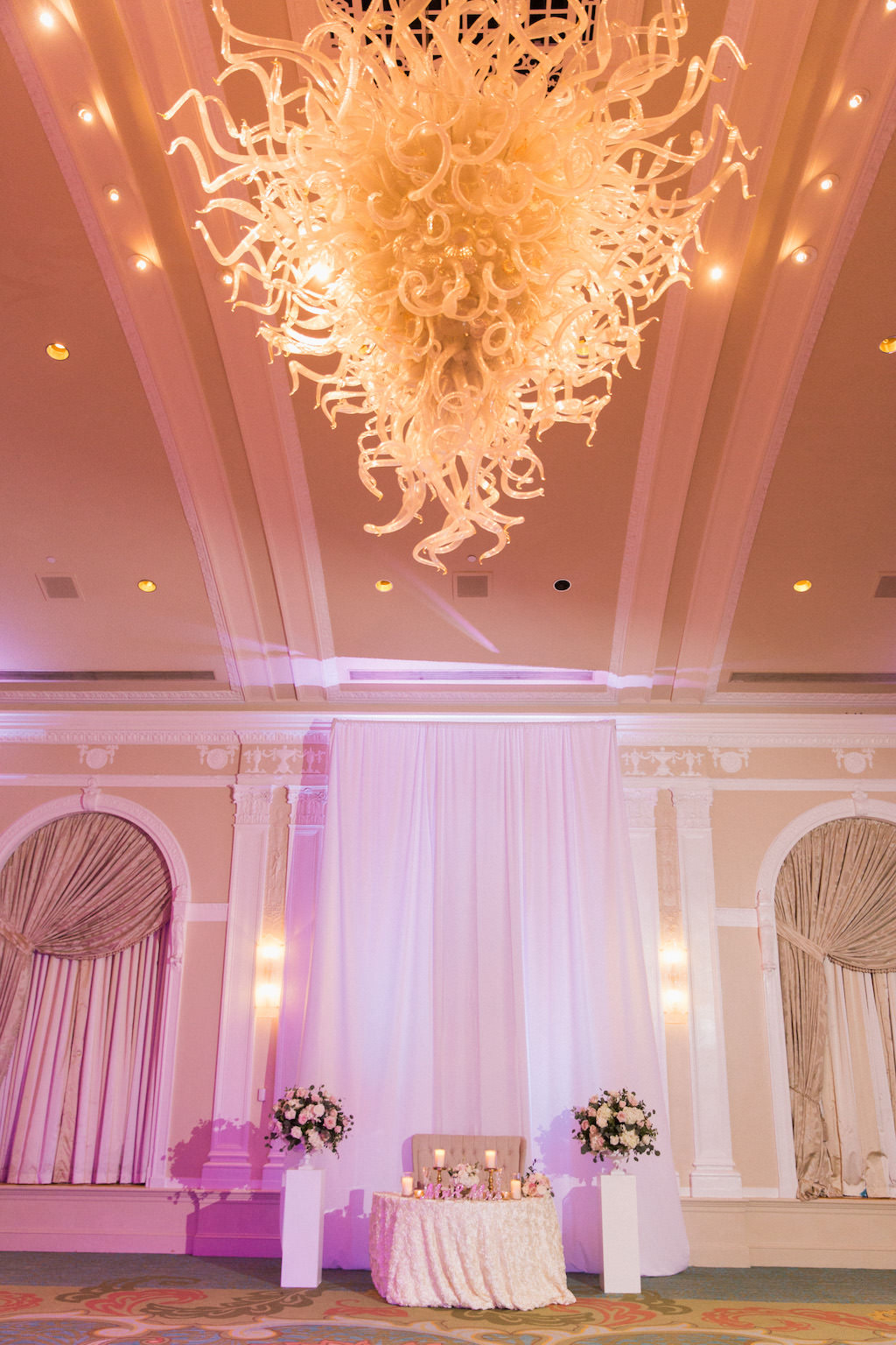Wedding Reception Sweetheart Table with Large Round Flower Arrangements on White Pedestals and Tall Candle Holders with Artistic Glass Chandelier | Tampa Bay Hotel Ballroom Wedding Venue The Vinoy Renaissance | St Pete Wedding Planner Parties A La Carte