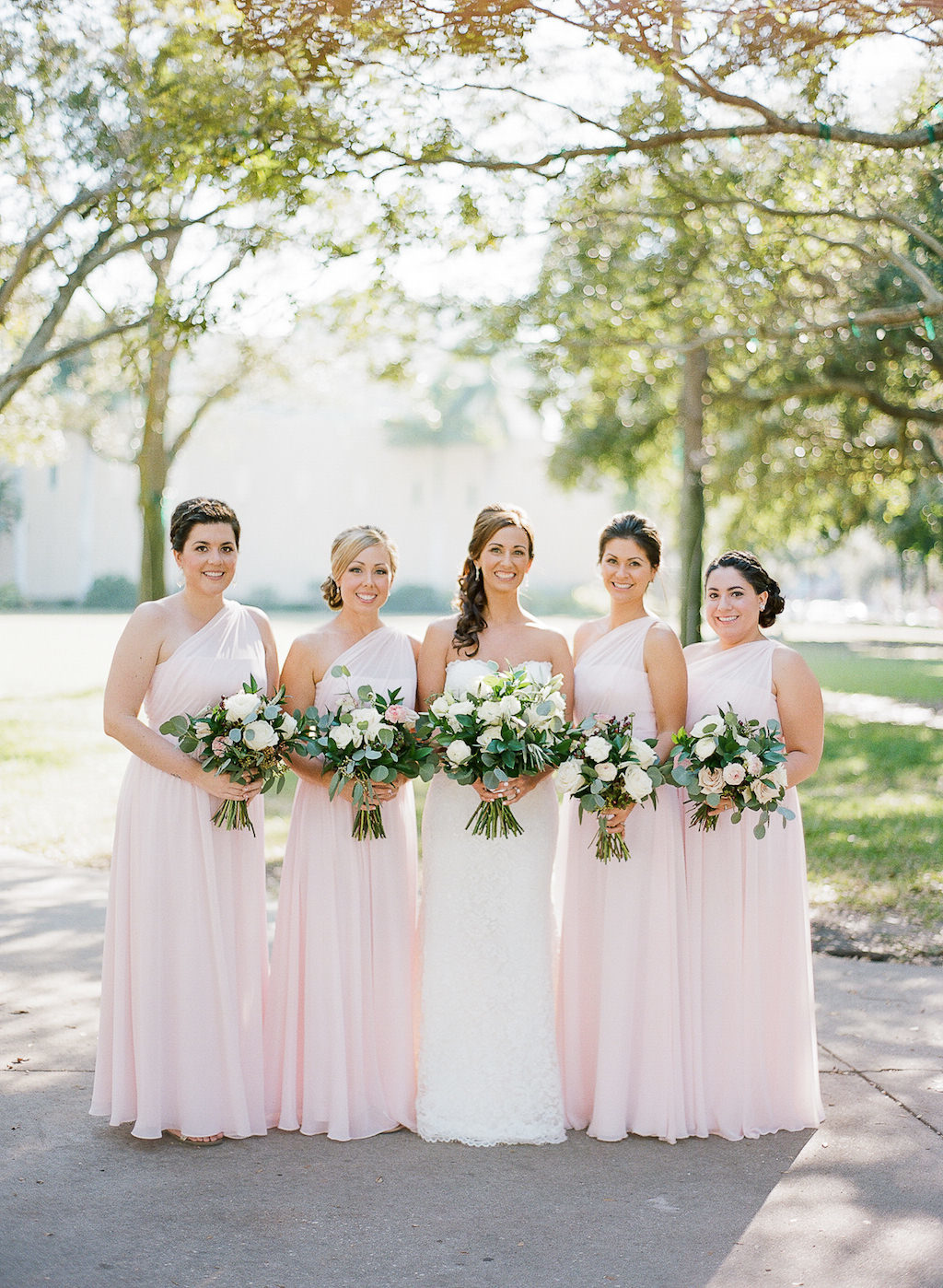 Outdoor Bridal Party Portrait with Asymmetrical One Shoulder Floor Length Blush Pink Bridesmaids Dresses and White with Greenery Bouquets | St. Petersburg Wedding Hair and Makeup Artist Michele Renee the Studio