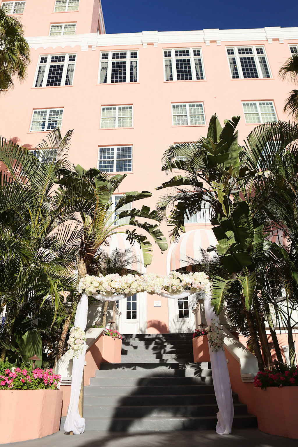 Outdoor Wedding Ceremony Arch Decor with Blush Pink and White Rose with Greenery Flowers and White Drapery | St Pete Beach Courtyard Garden Wedding Ceremony Venue The Don Cesar