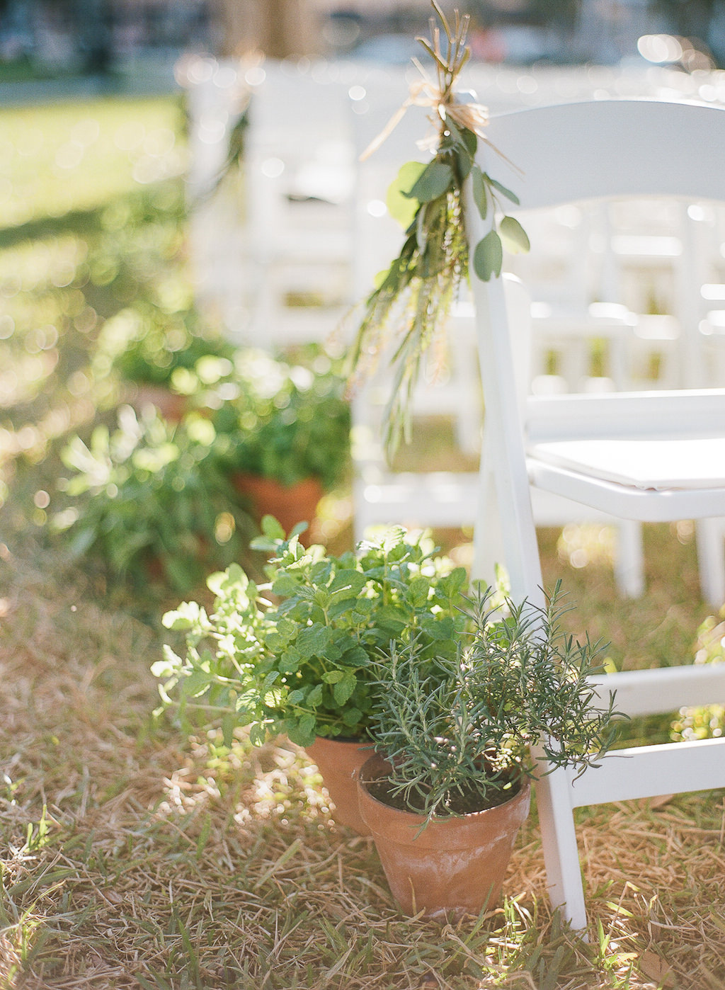 Natural Organic Outdoor Wedding Ceremony Decor with Ceramic Pots of Fresh Herbs, Greenery Bundles and Folding White Chairs | Tampa Bay Wedding