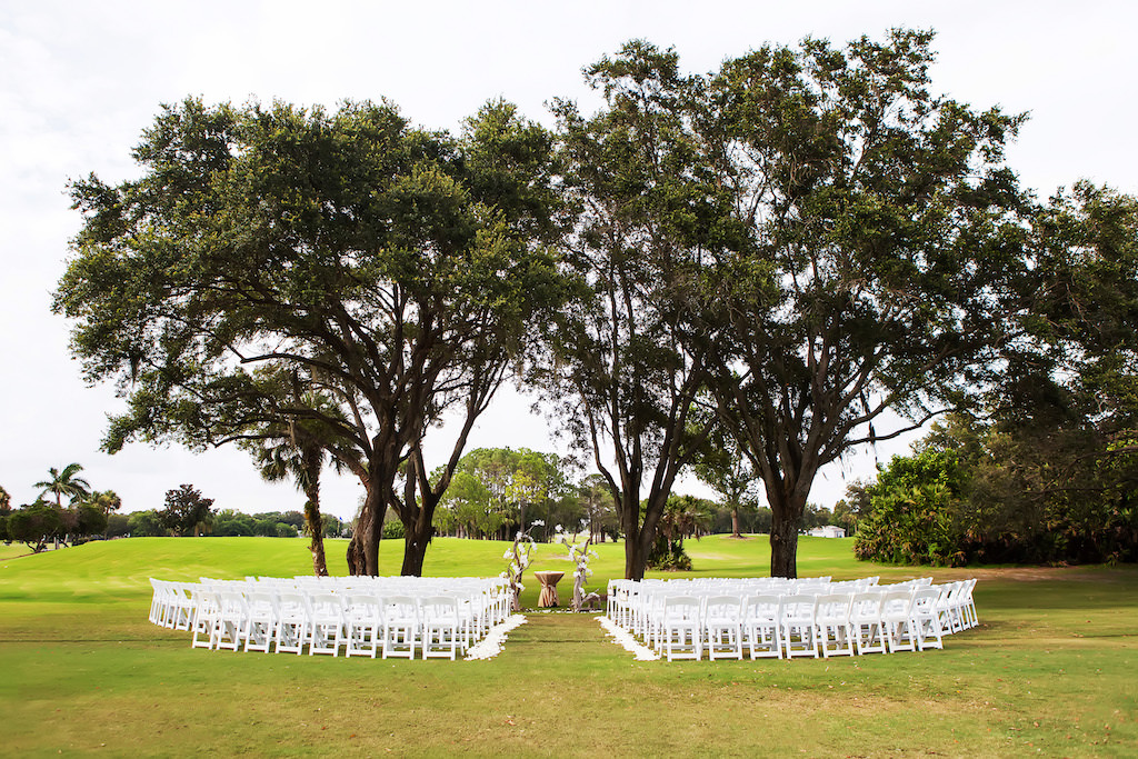 Outdoor Ceremony With Natural Driftwood and Floral Arch and White Folding Chairs | Clearwater Wedding Venue Countryside Country Club