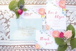 Summer Floral Wedding Invitation Suite with Light Blue Envelope, Pink and Gold Hand Lettering, and Peach and Yellow Roses