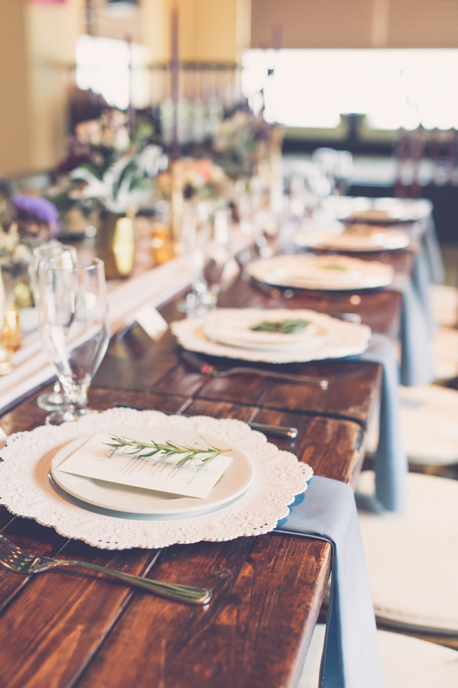 Boho Wedding Reception Table Decor with Long Wooden Table with Blush Runner, Gray Napkins, Gold Accents, and Lace Porcelain Chargers with Rosemary | Tampa Farm Table Rentals A Chair Affair