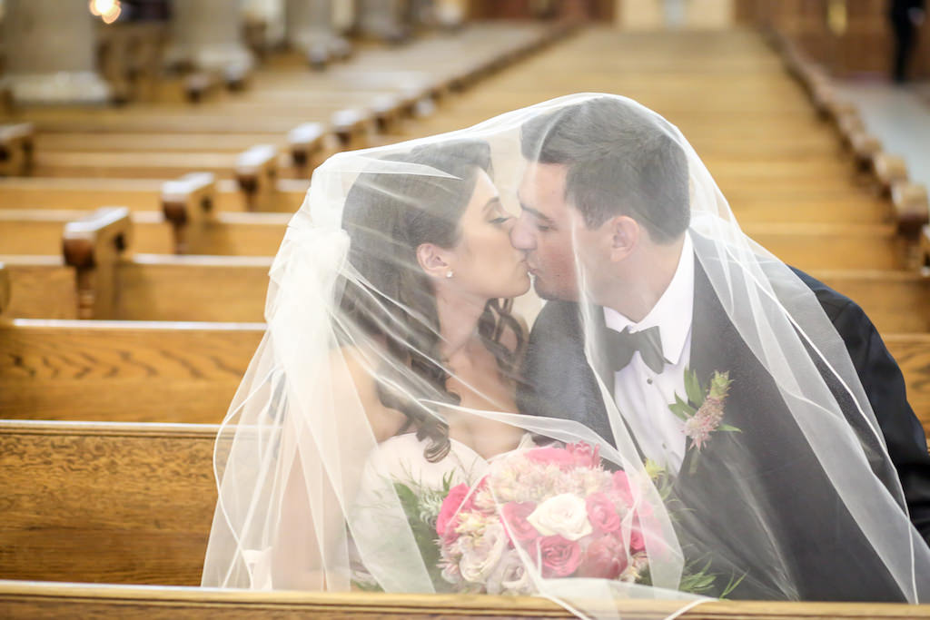 Traditional Church Wedding Ceremony Portrait, Bride and Groom Under Veil with Tropical Pink, Magenta Rose, and Greenery Bridal Bouquet and Boutonniere | Tampa Wedding Ceremony Venue Sacred Heart Catholic Church | Tampa Wedding Photography Lifelong Studios | Planner Special Moments Event Planning