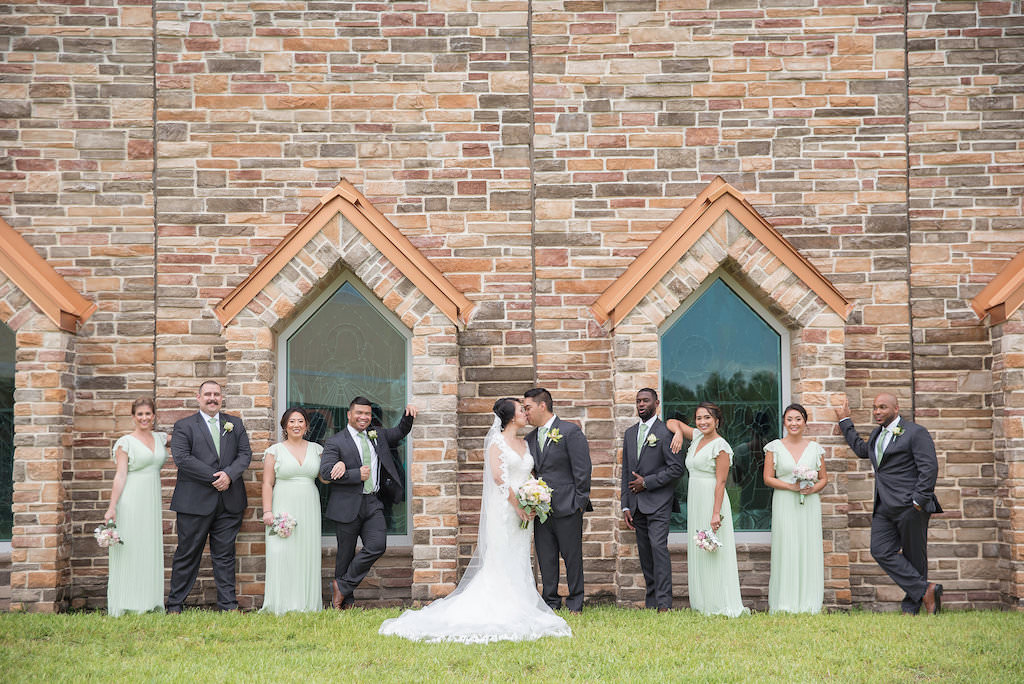Outdoor Wedding Party Portrait with Church Windows, Bride in V Neck Stella York Wedding Dress, Bridesmaids in Floor Length V Neck Light Green Dresses, Groomsmen with Light Green Ties and Yellow Boutonnieres | Tampa Bay Wedding Photographer Kristen Marie Photography