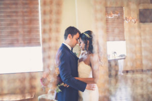 Bride and Groom First Dance Portrait, Bride with Small Floral Headband Hair Accessory and Peach and Burgundy Bouquet, Groom in Blue Suit