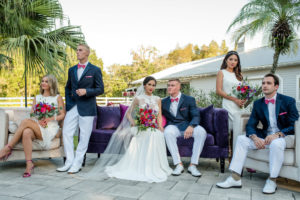 Retro Southern Inspired Wedding Party Outdoor Patio Portrait, Groomsmen in Navy Jackets, White Pants and Shoes, and Hot Pink Bow Ties | Red and Purple with Greenery Bouquet from Northside Florist | Classic Bridesmaids Dresses Truly Forever Bridal | Daalarna Couture Illusion Lace Wedding Dress from The Bride Tampa | Lutz Florida Wedding Venue Southern Plantation Oasis | Tampa Wedding Planner Exquisite Events | Caroline & Evan Photography