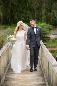 Outdoor Garden Bride and Groom Wedding Portrait on Wooden Bridge, Bride in Lace Ballgown Wedding Dress from Tampa Bridal Store The Bride Tampa, Groom in Gray Tuxedo, with White Floral and Greenery Bouquet | Tampa Wedding Photographer Andi Diamond Photography | Tampa Bay Garden Wedding Venue The Palms Tampa Golf And Country Club | Florist Gabro Event Services