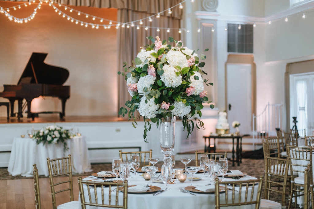 Blush and Gold Wedding Reception with Extra Tall Hydrangea and Pink with Greenery Centerpiece in Tall Glass Vase, Gold Chiavari Chairs, and String Lights | Tampa Bay Wedding Rentals A Chair Affair | St Pete Wedding Venue St Petersburg Woman's Club | Lighting Nature Coast Entertainment Services