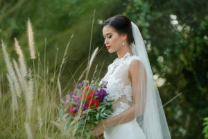 Outdoor Bridal Portrait in Floral Lace Cutout Wedding Dress with Red, Purple, and Greenery Bouquet | Tampa Bay Dress Boutique The Bride Tampa | Photography by Caroline & Evan Photography | Hair and Makeup Michele Renee The Studio